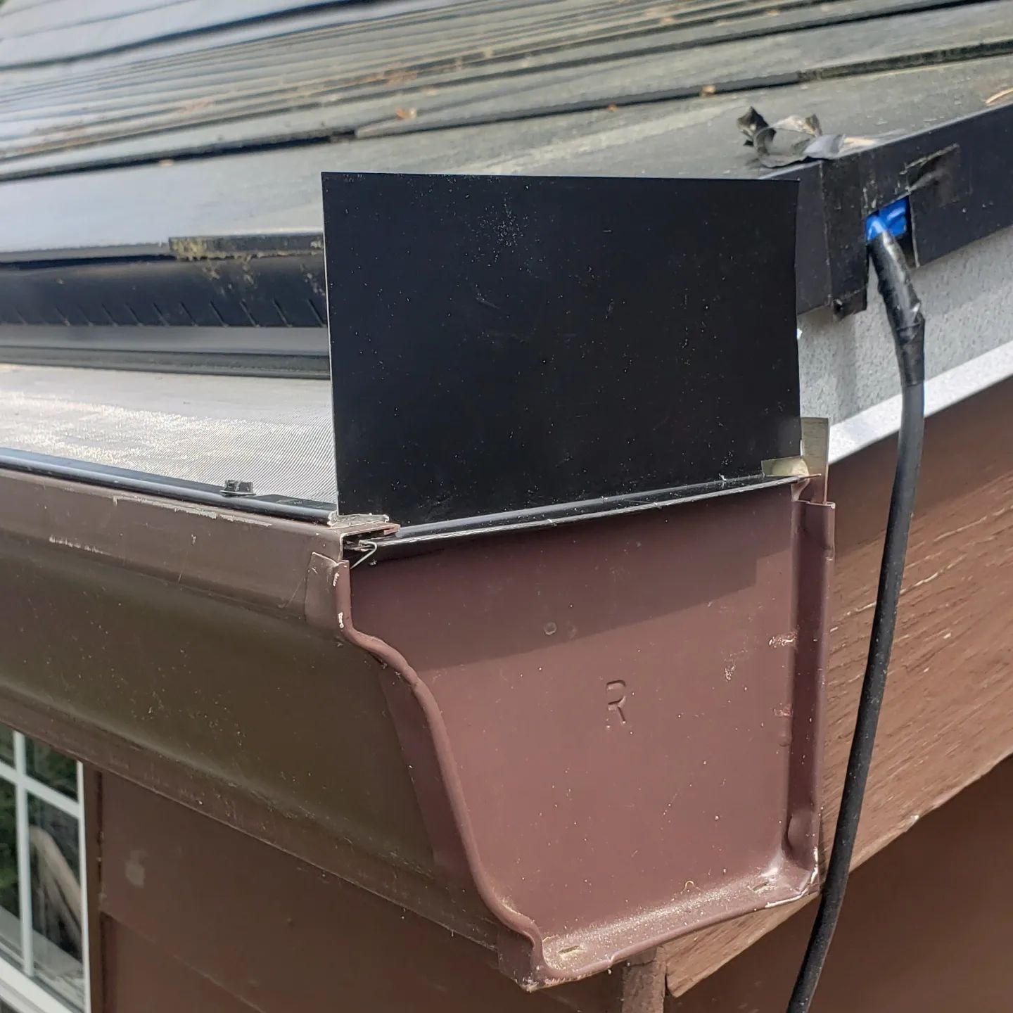 A brown gutter is attached to the side of a building.