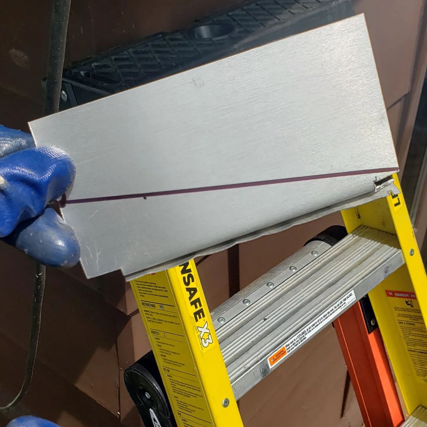 A person is cutting a piece of metal on a ladder