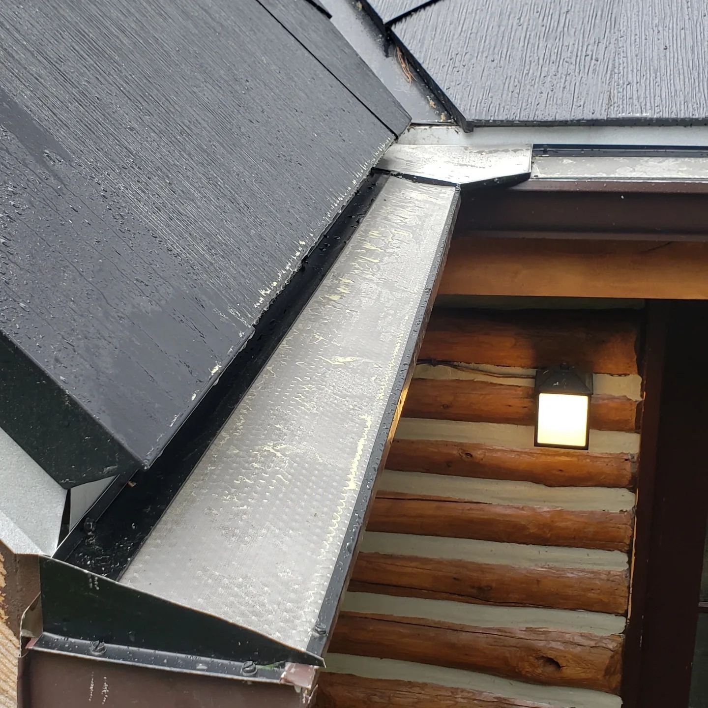 A log cabin with a black roof and gutters