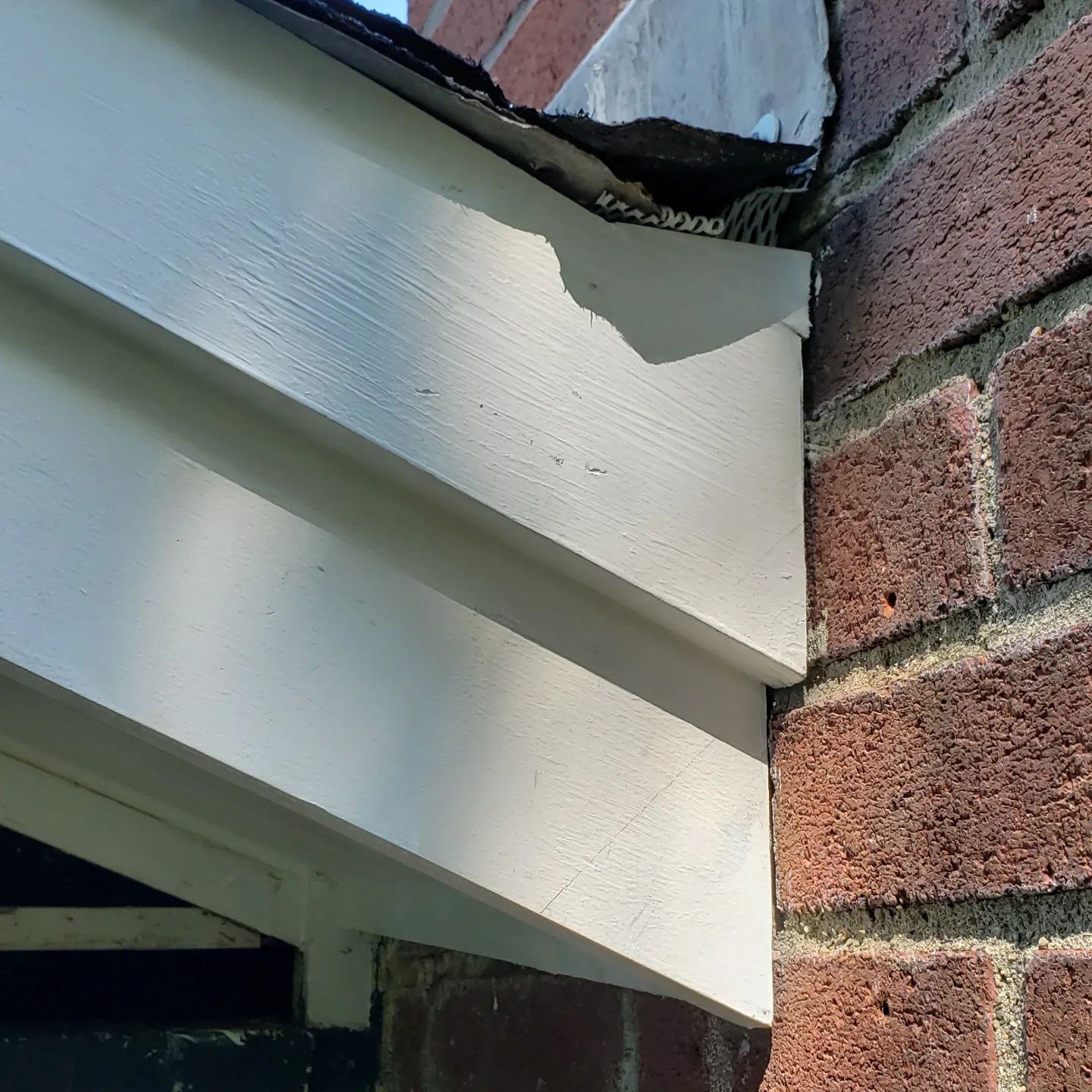 A close up of a white siding on a brick wall