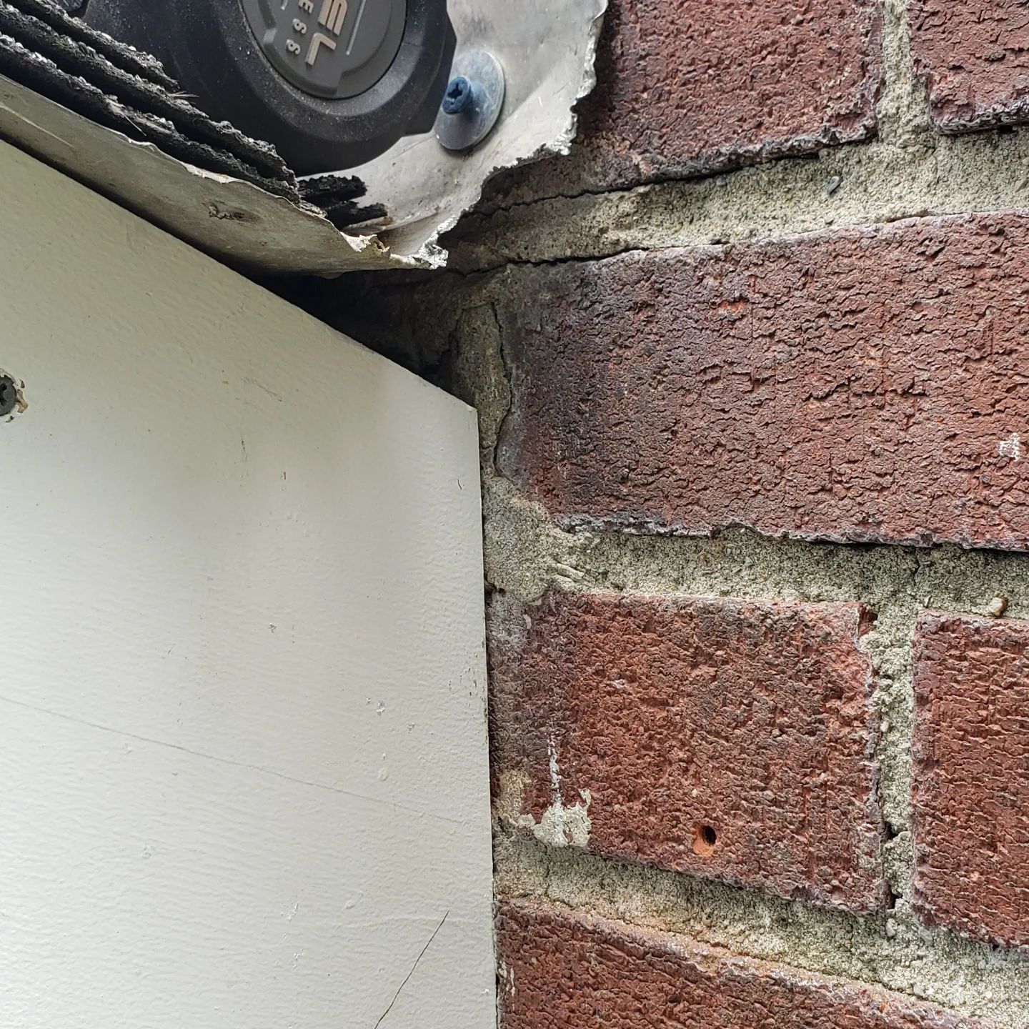 A brick wall with a white door and a clock on it.