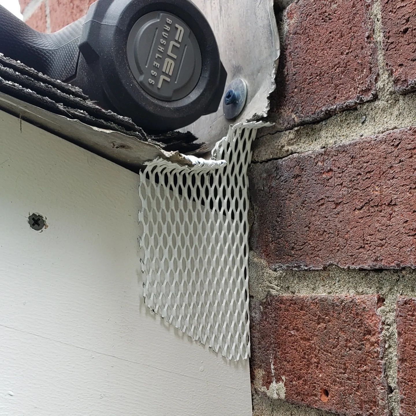 A drill is sitting on top of a brick wall.