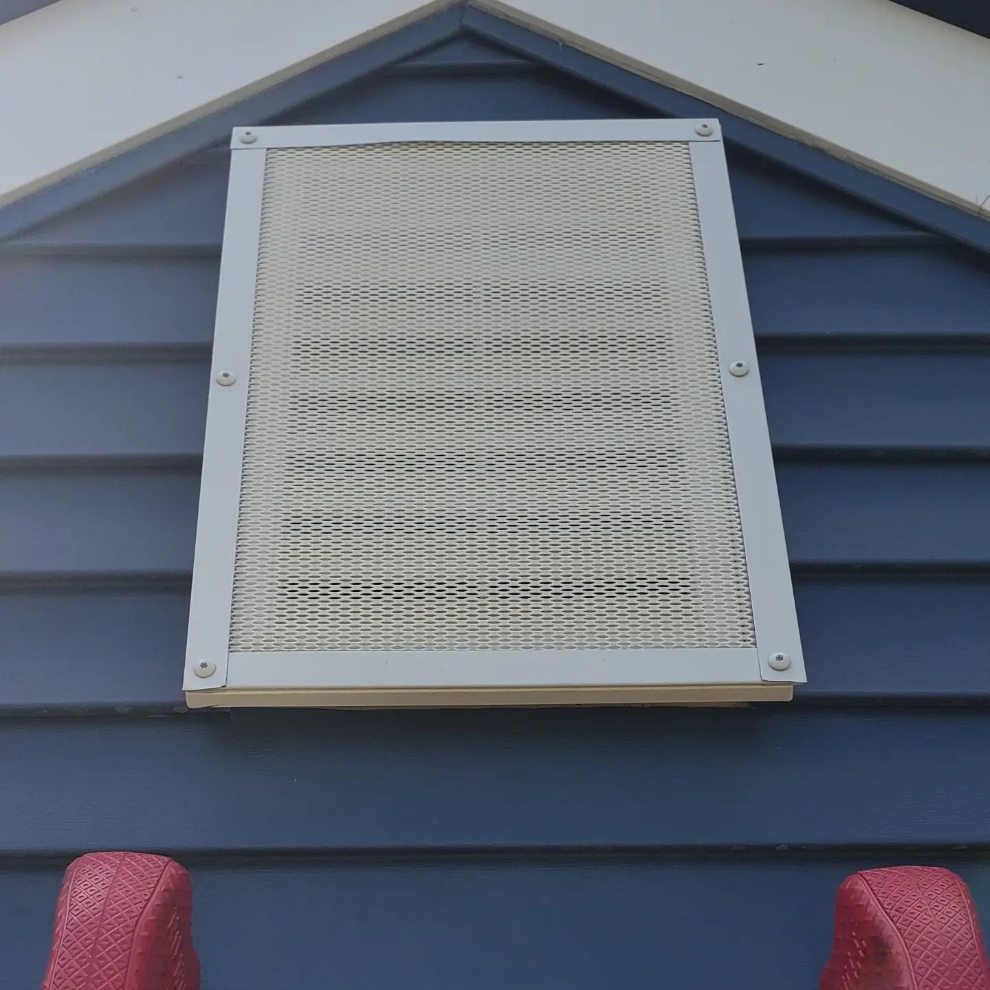 A blue house with a white grille on the side
