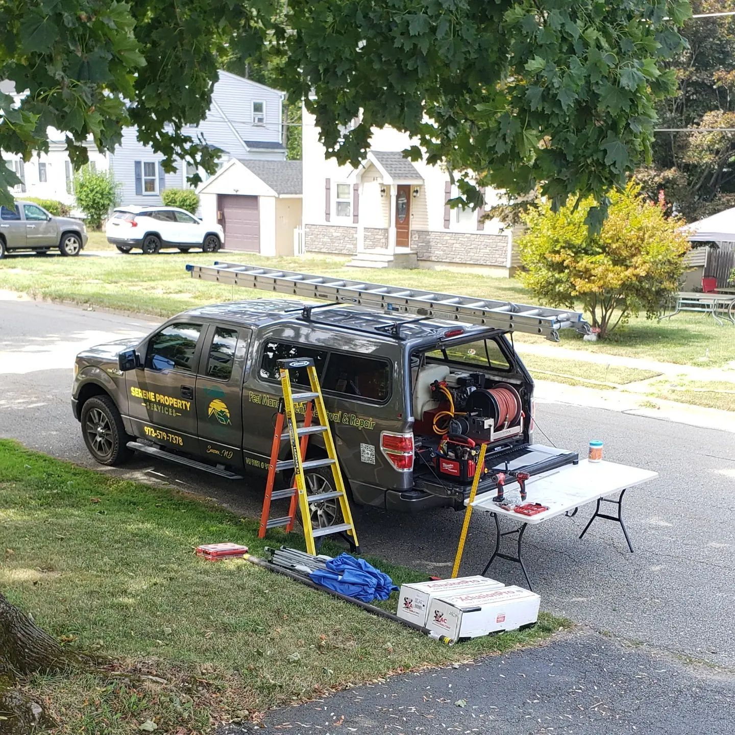 A truck with a ladder on top of it is parked on the side of the road.