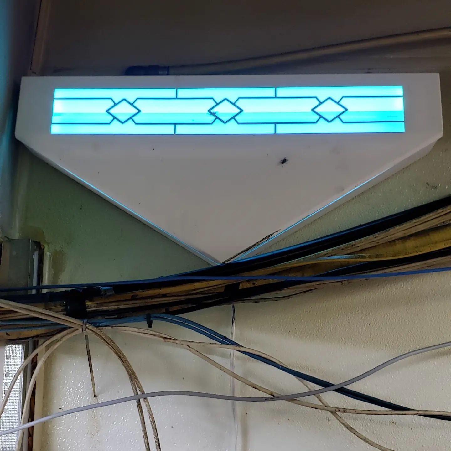 A blue light is hanging from the ceiling above a bunch of wires