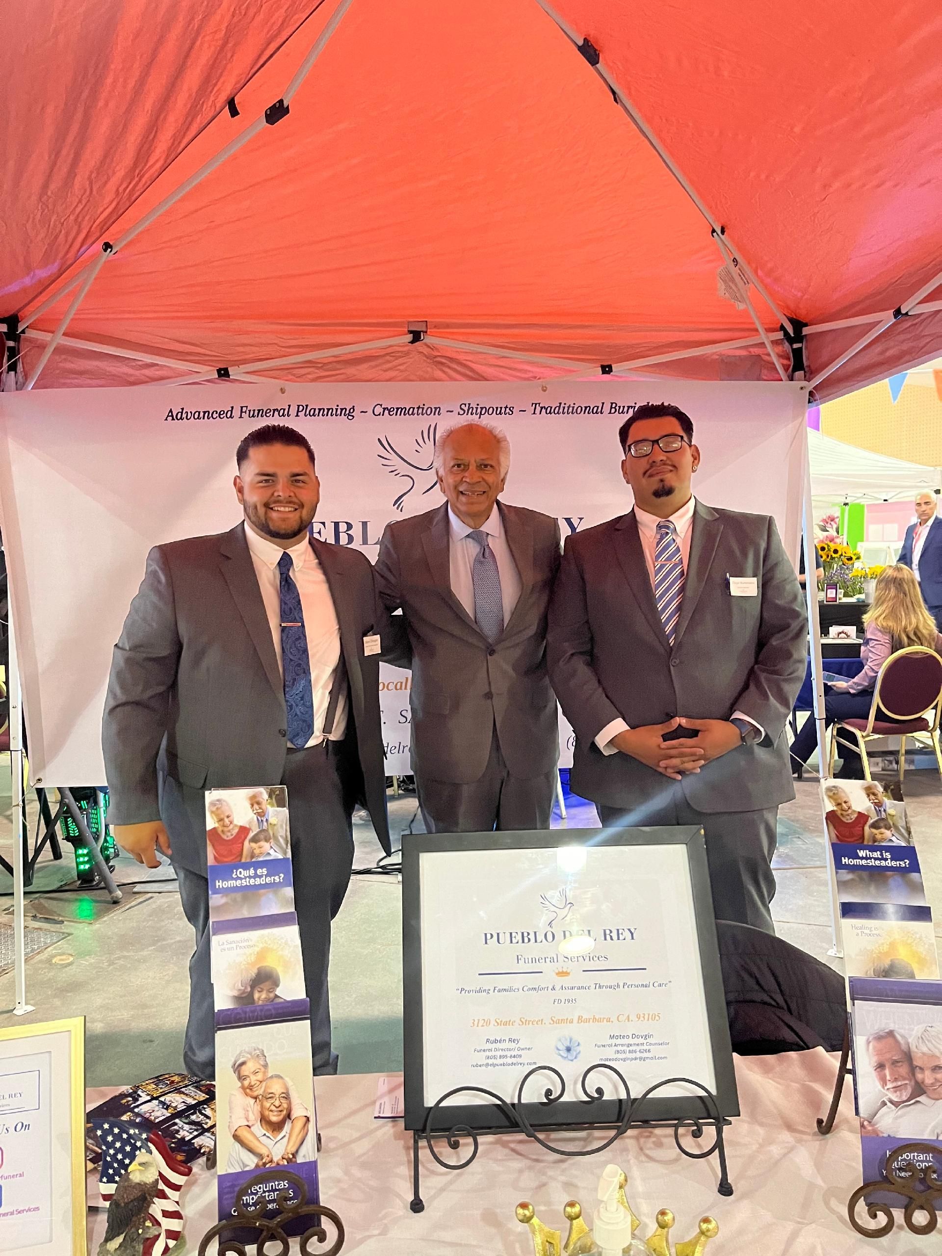 Fountain in a park with palm trees in the background under a cloudy sky.