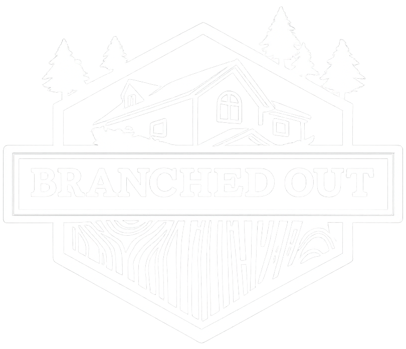 A white logo on a black background featuring a house outline, pine trees, and a wood-grain pattern inside a hexagon.