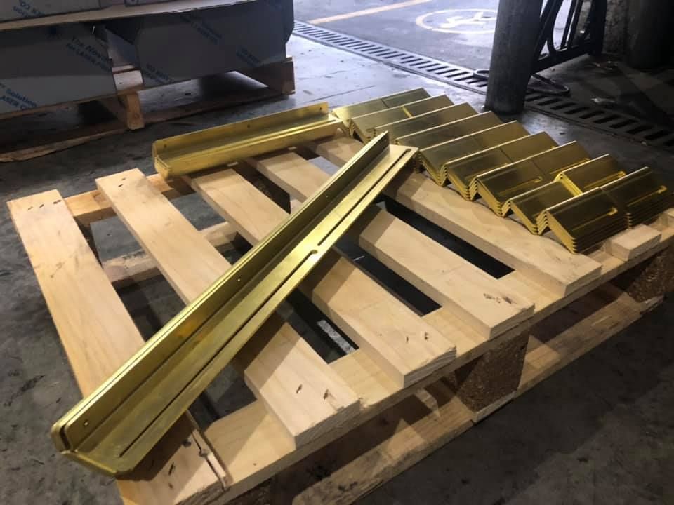 A wooden pallet with a bunch of brass pieces.