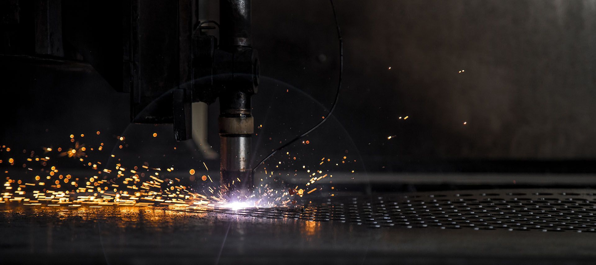 A machine is cutting a piece of metal with sparks coming out of it.