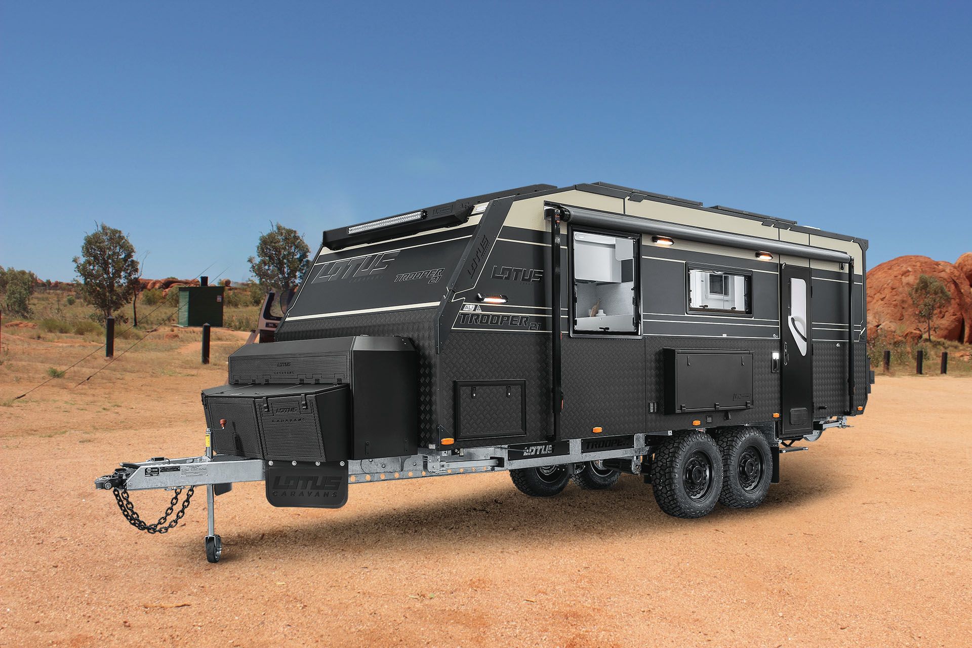 A black trailer is parked in the middle of a desert.