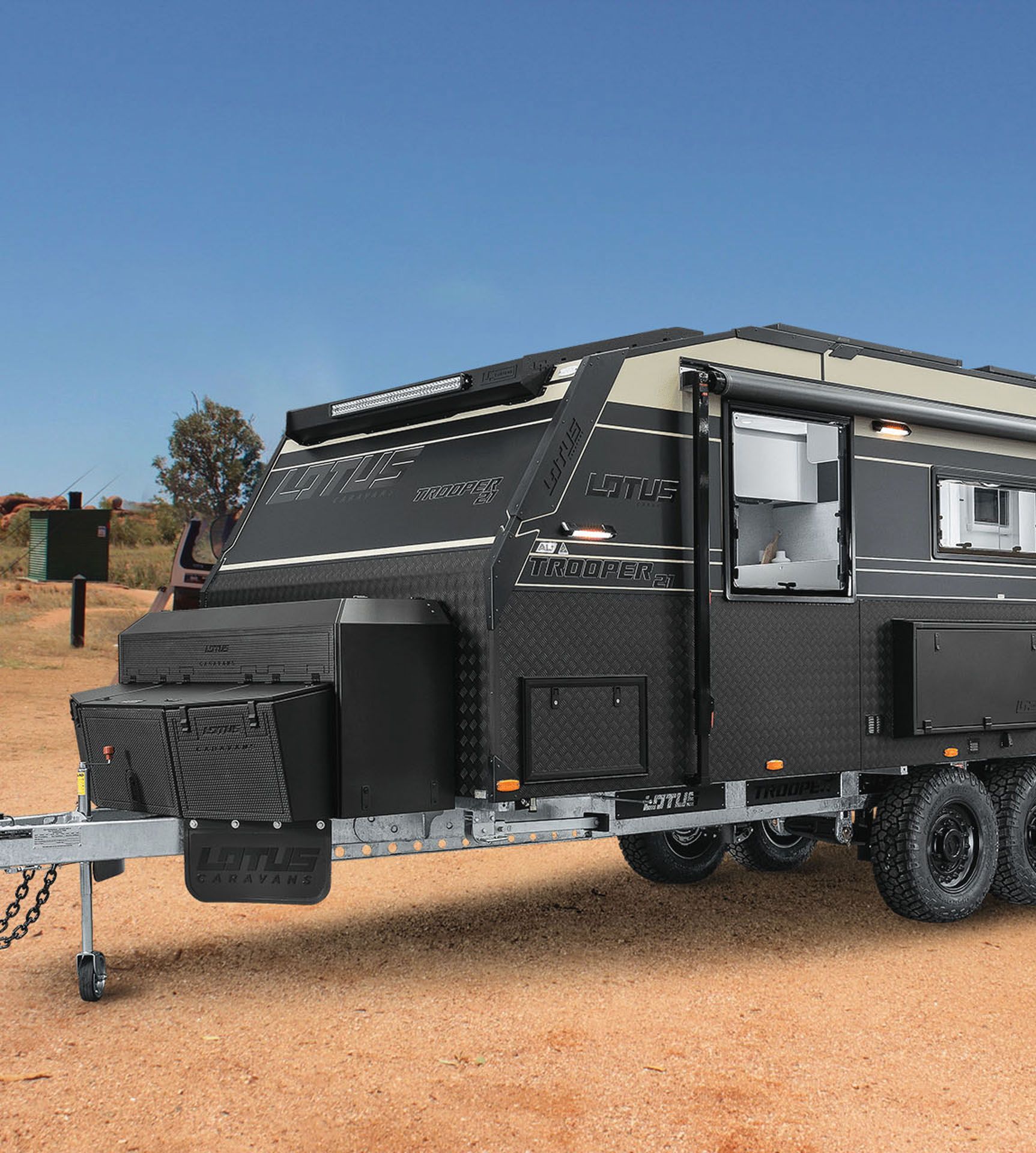 A black caravan is parked in the middle of a desert.