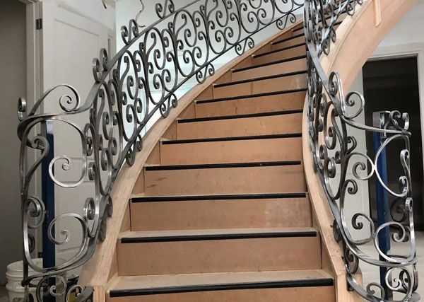 A wooden staircase with a wrought iron railing in a house.