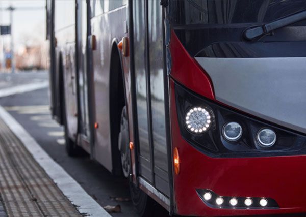 A red and white bus is parked at a bus stop.