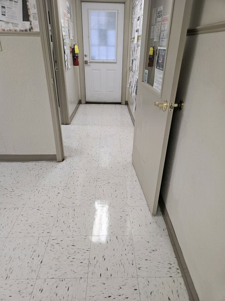 A hallway with a white tile floor and a white door.