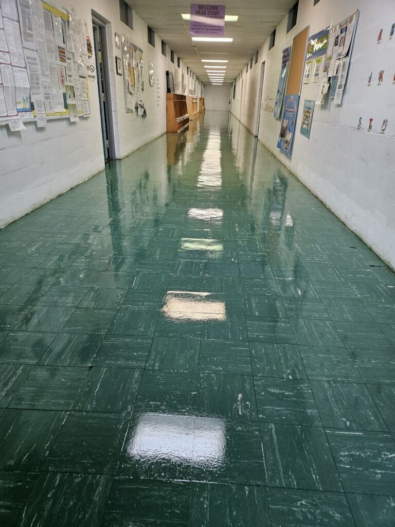 A long hallway with green tile floors and white walls