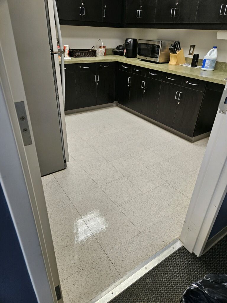 A kitchen with black cabinets and a white tile floor