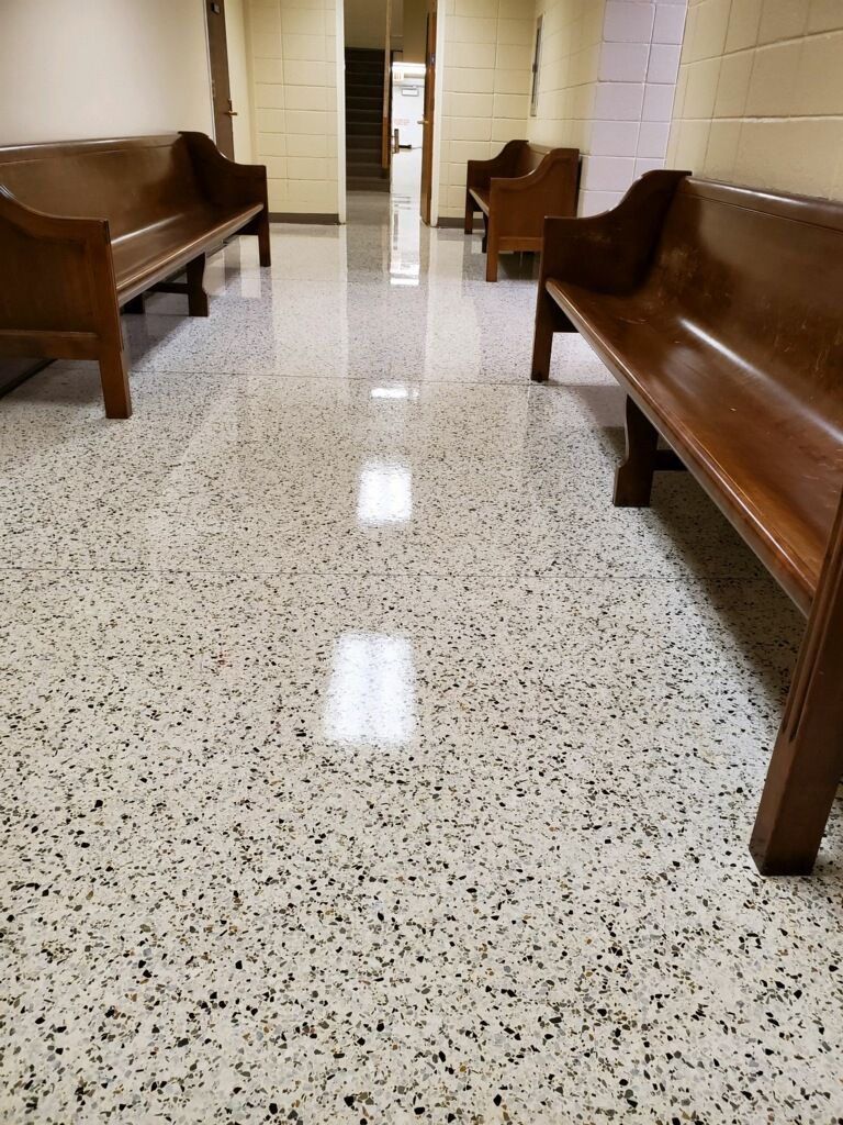 A hallway with wooden benches and a white floor.