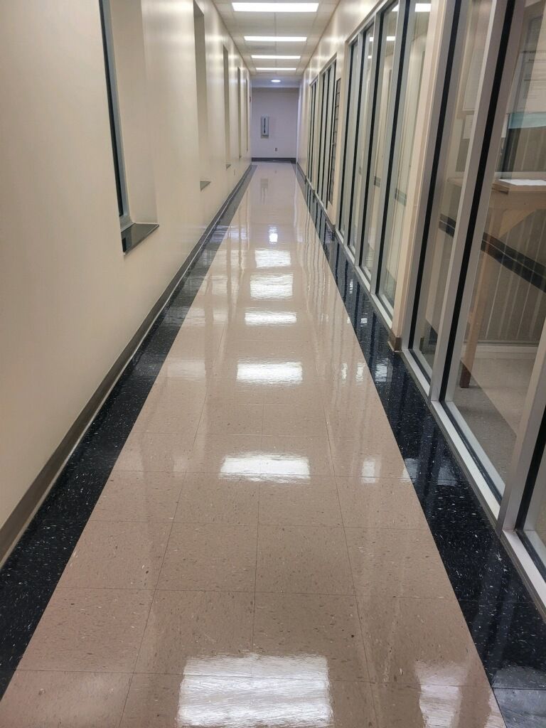 A long hallway with a lot of windows and a shiny floor.