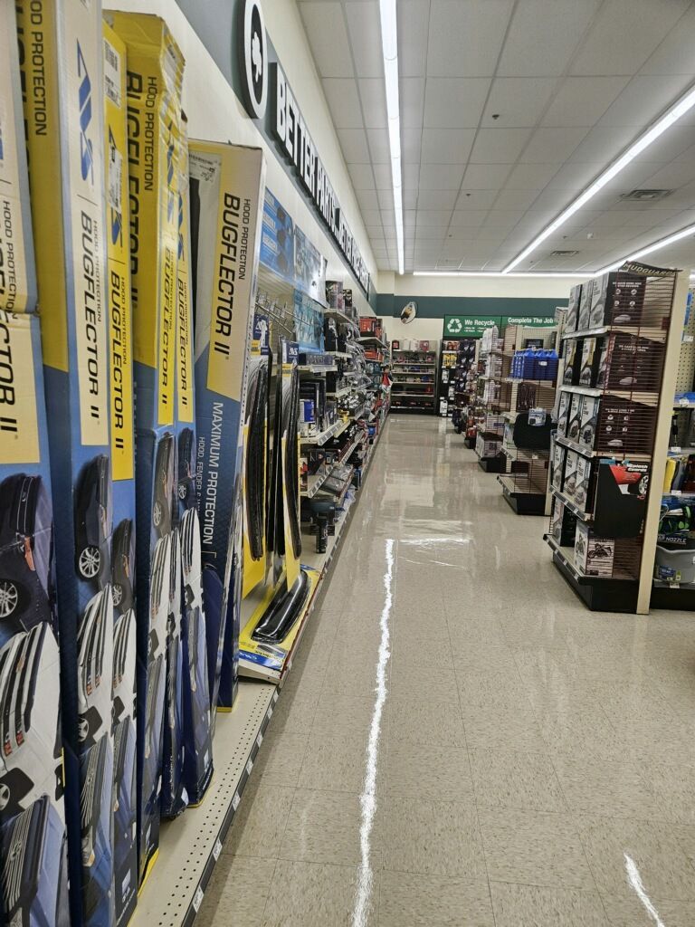 A row of wiper blades are lined up on a shelf in a store.