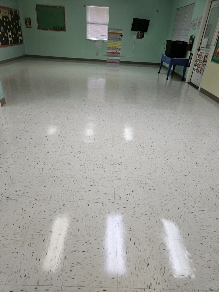 A large empty room with a white tile floor and green walls.