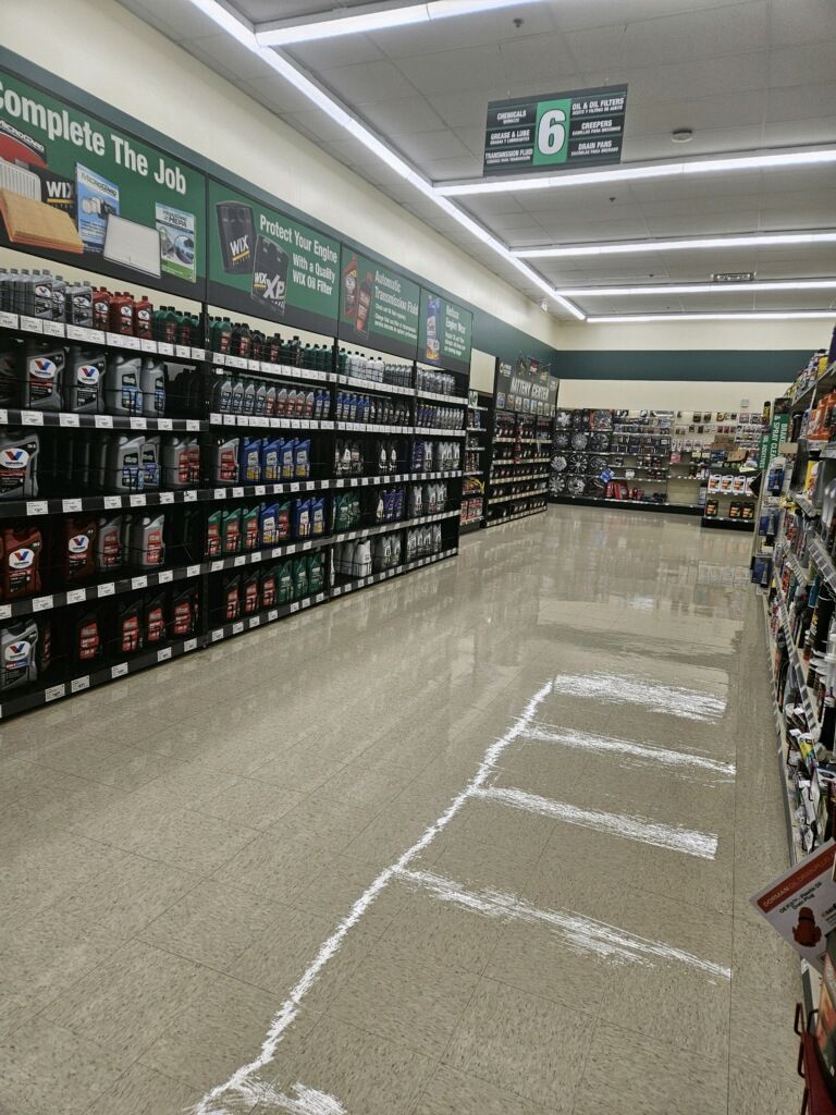 The inside of a grocery store with a chalk drawing of a parking spot on the floor.