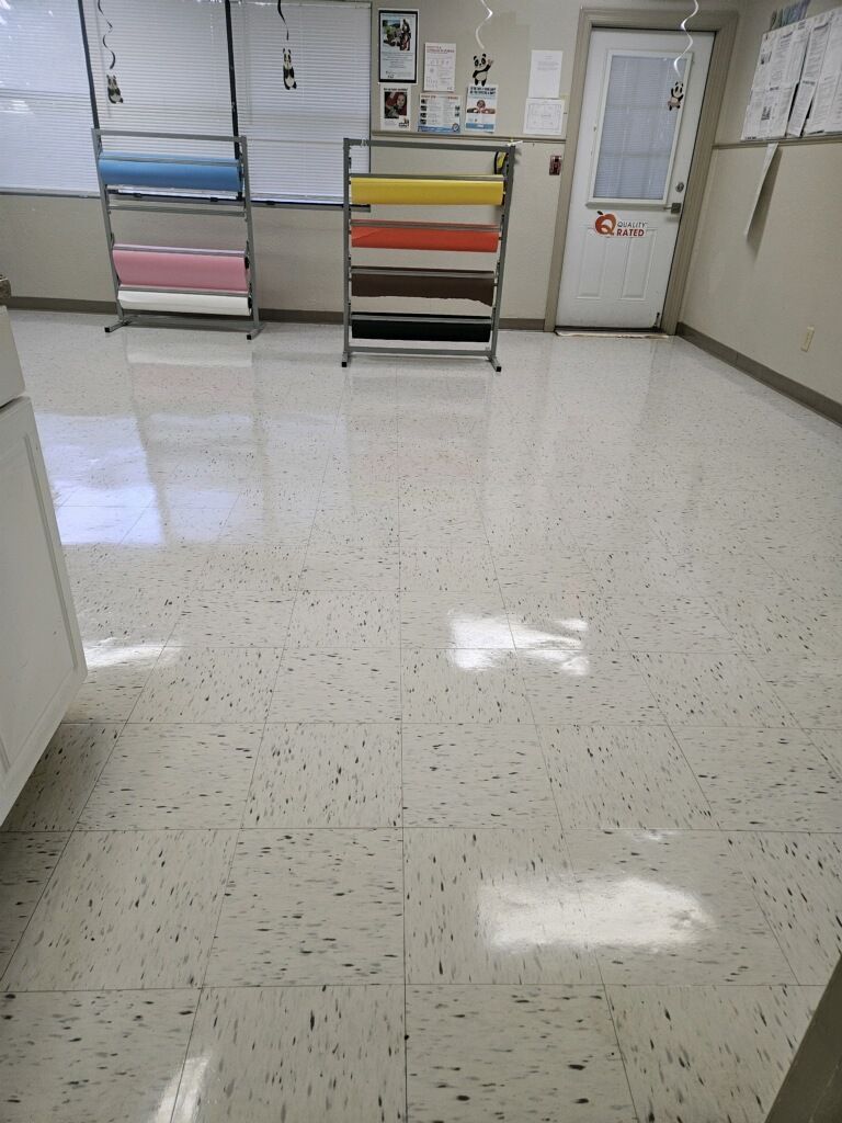 A room with a white tile floor and a shelf with rolls of paper on it.