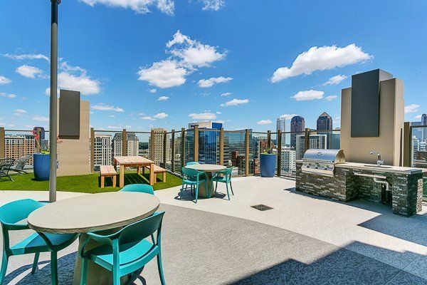 A rooftop patio with tables and chairs and a grill.