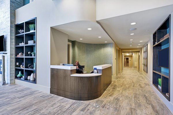 A woman is sitting at a reception desk in a hallway.