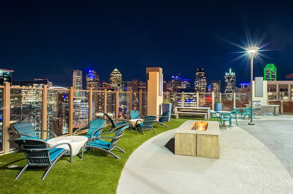 A rooftop patio with a fire pit and chairs at night.