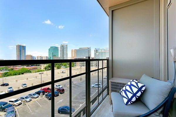 A balcony with a chair and a view of a parking lot.