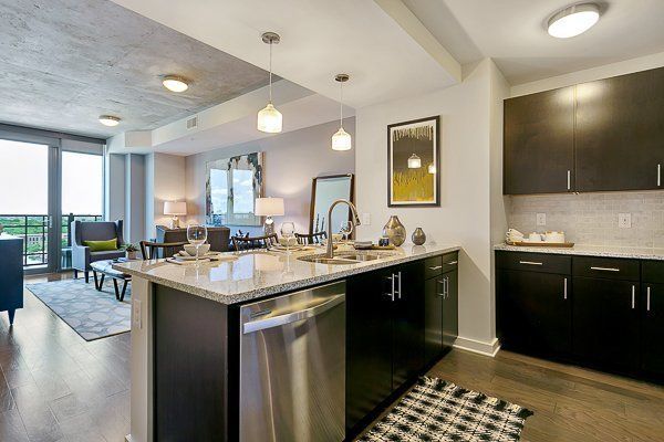 A kitchen with stainless steel appliances , black cabinets and a large island.