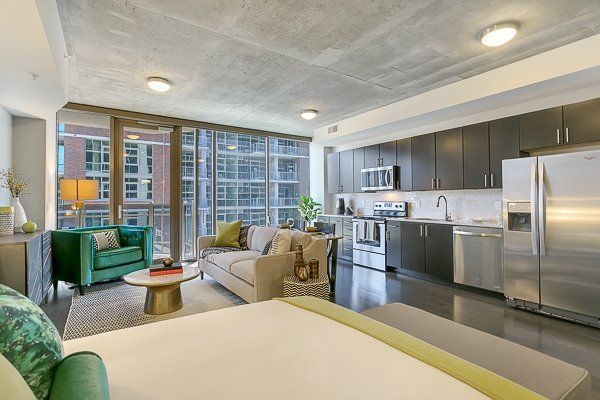 A living room with a couch , chair , table and refrigerator.