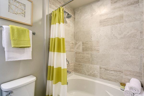 A bathroom with a bathtub , toilet , shower curtain and towels.