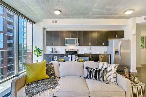 A living room with a couch and a kitchen in the background.