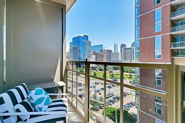 A balcony with a striped chair and a view of a city.