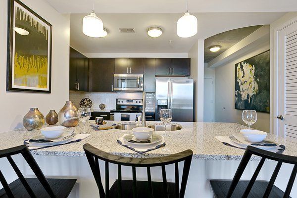 A kitchen with a dining table and chairs and a stainless steel refrigerator.