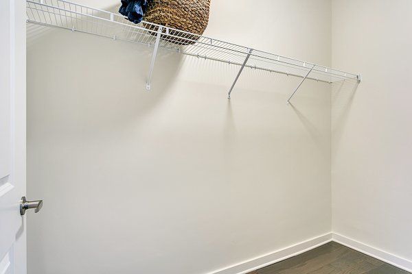 An empty walk in closet with a basket hanging on the wall.