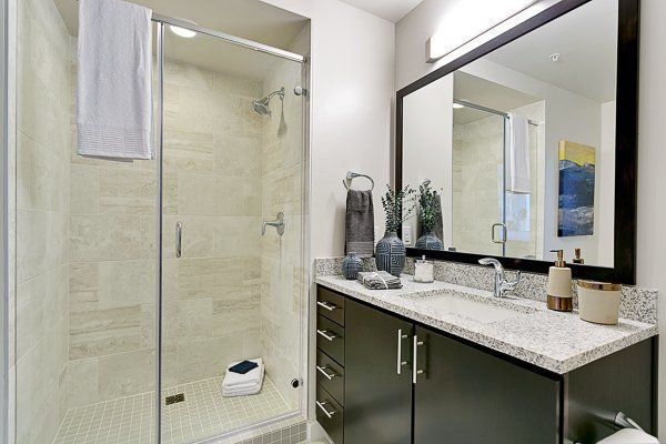 A bathroom with a sink , mirror and walk in shower.