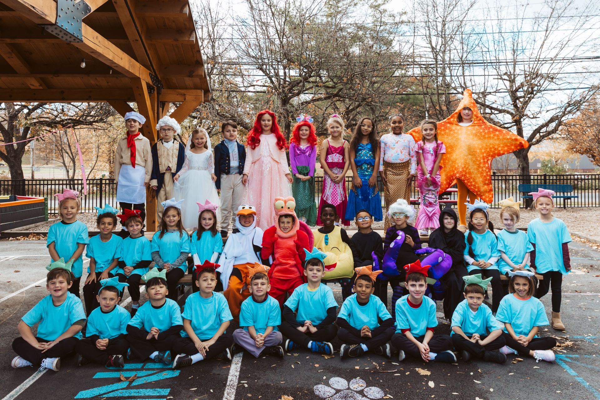 Children in costumes pose outside, including princesses, a starfish, and others.