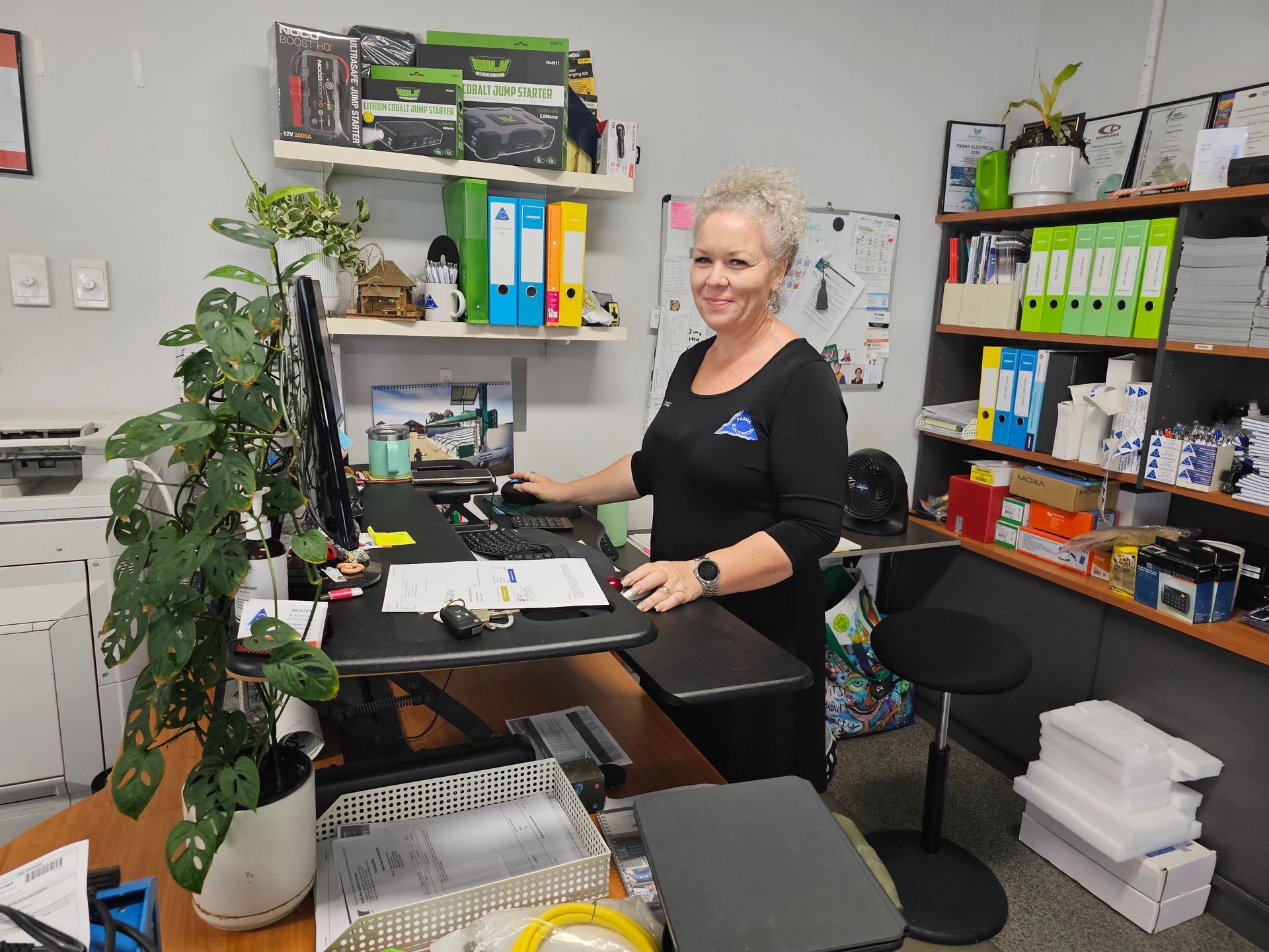 A Woman Is Sitting At A Desk In Front Of A Computer — PASMA Electrical In Portsmith, QLD