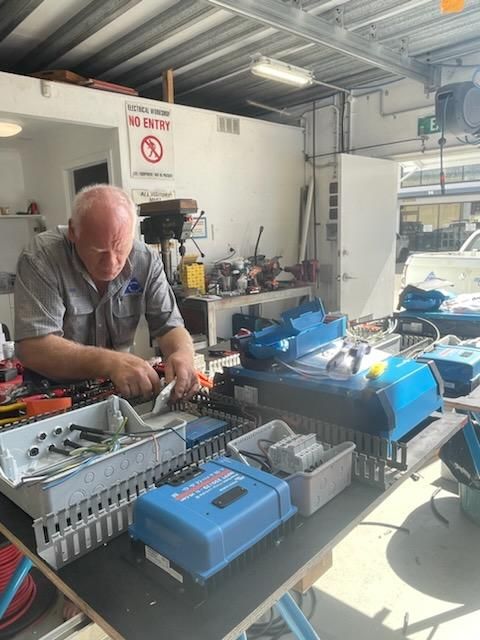 A Man Is Working On A Machine In A Garage — PASMA Electrical In Portsmith, QLD