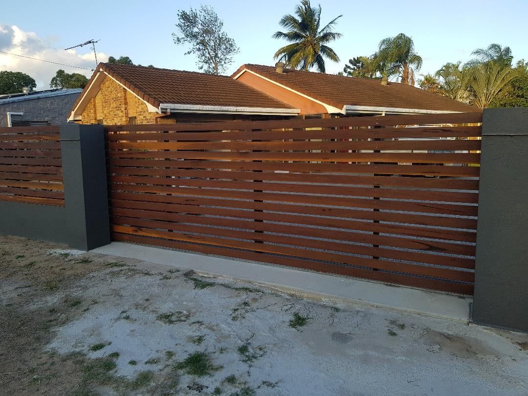 A Wooden Fence With a House in the Background — Mackay Hardwood Sales in Cannonvale, QLD