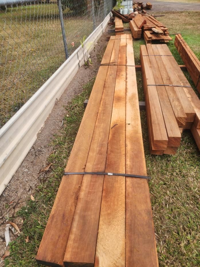 A Bunch of Wood Sitting on Top of a Lush Green Field — Mackay Hardwood Sales in Moranbah, QLD