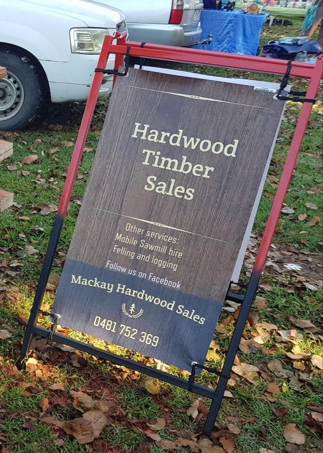 A Sign for Hardwood Timber Sales is Sitting in the Grass — Mackay Hardwood Sales in Freshwater Point, QLD