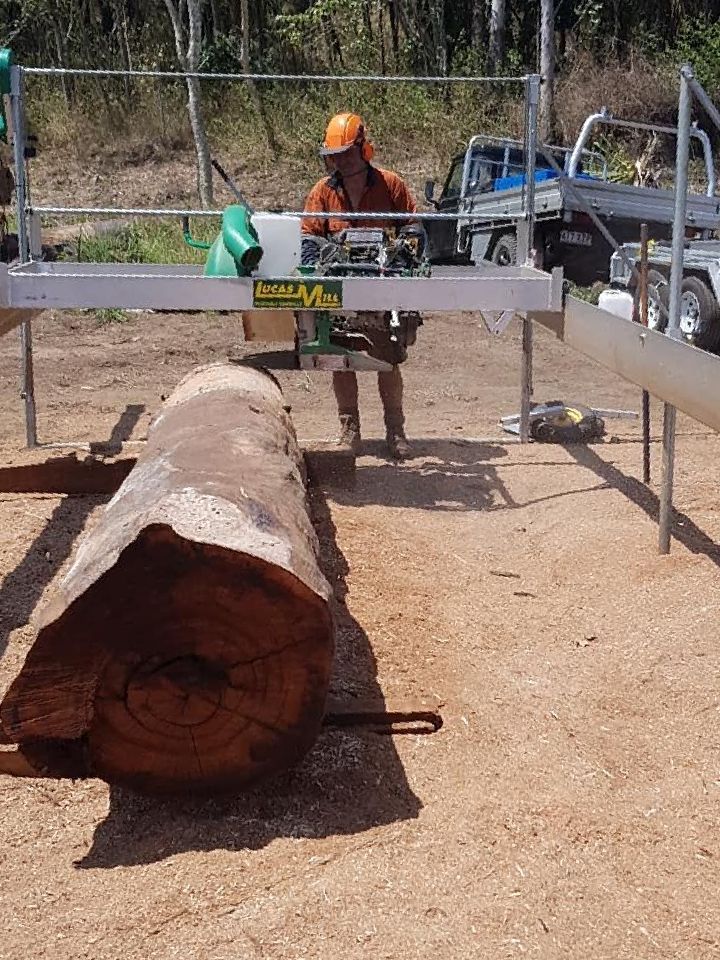 A Man is Cutting a Large Log With a Chainsaw — Mackay Hardwood Sales in Freshwater Point, QLD
