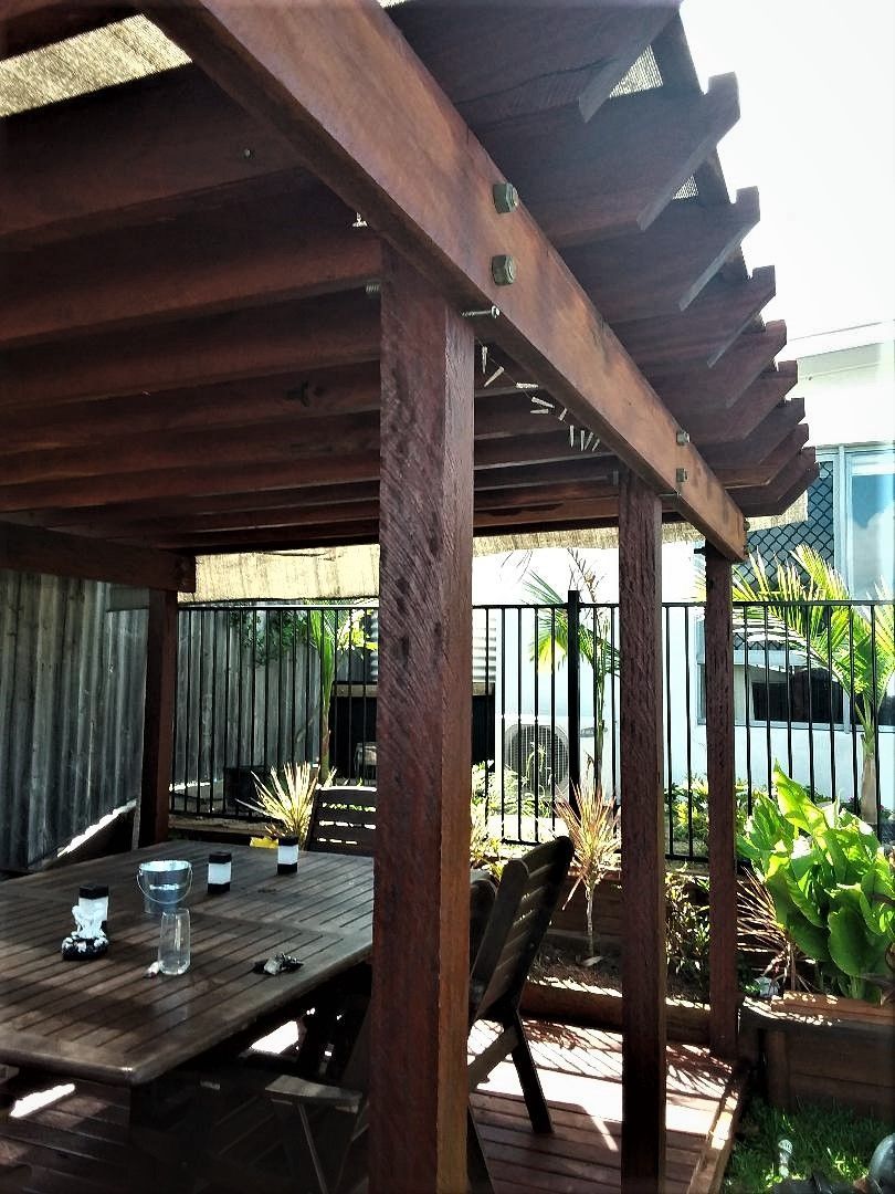 A Wooden Pergola With a Table and Chairs Underneath It — Mackay Hardwood Sales in Freshwater Point, QLD