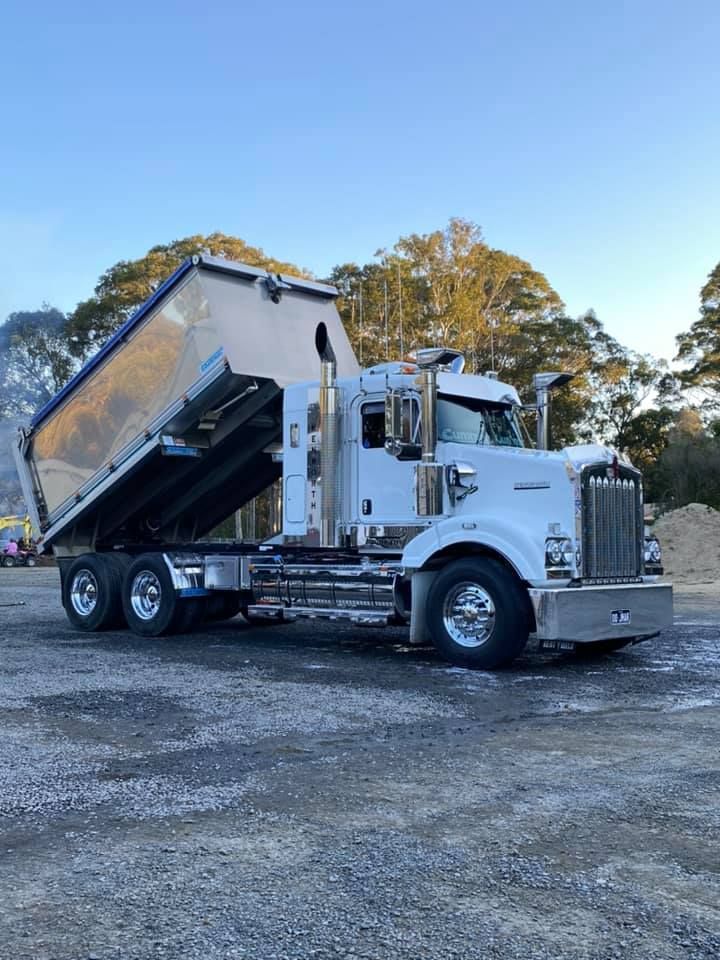 A White Dump Truck Is Parked In A Gravel Lot — JMAK Haulage & Landscapes Supplies In Falls Creek, NSW
