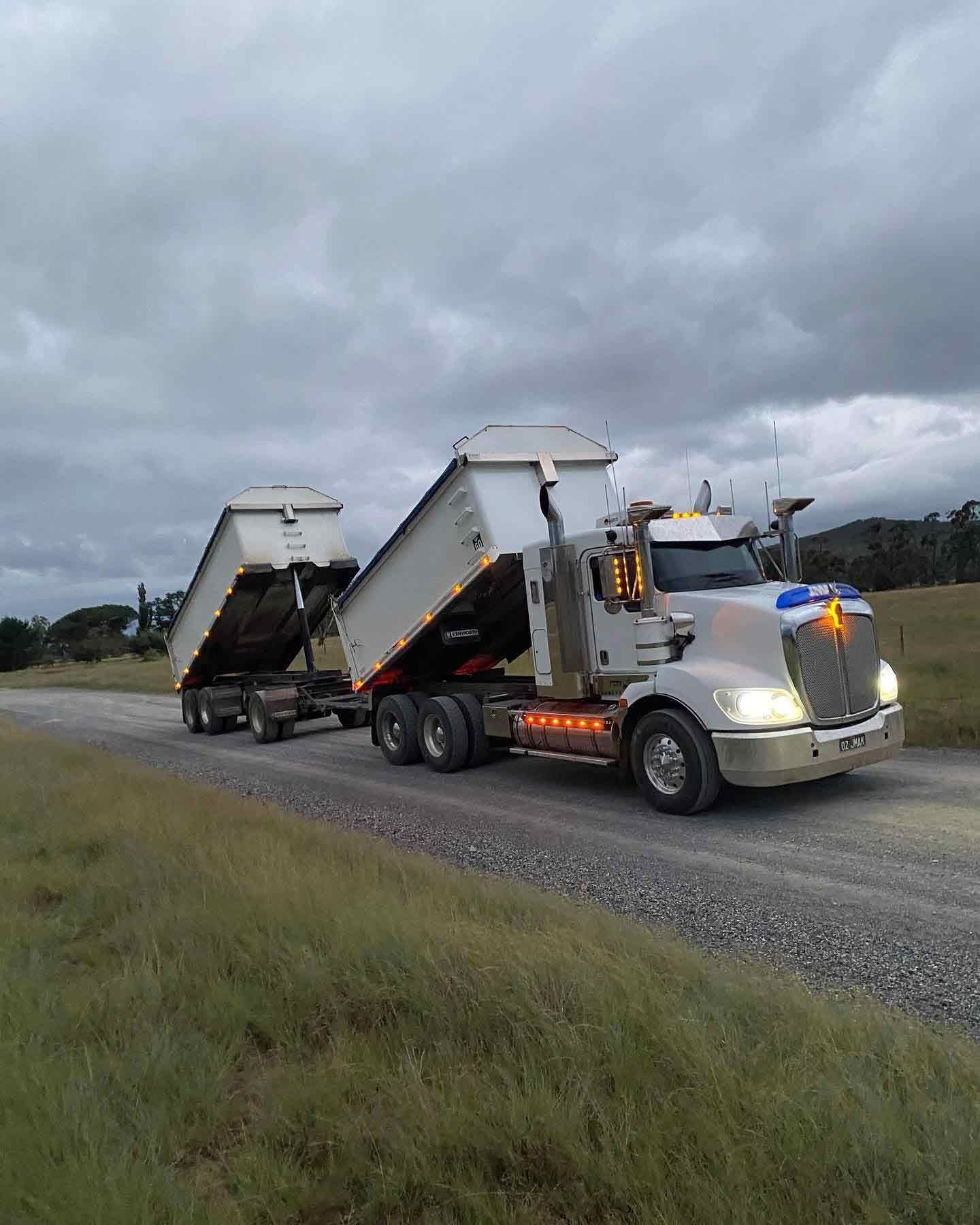 A Dump Truck Is Driving Down A Dirt Road — JMAK Haulage & Landscapes Supplies In Huskisson, NSW