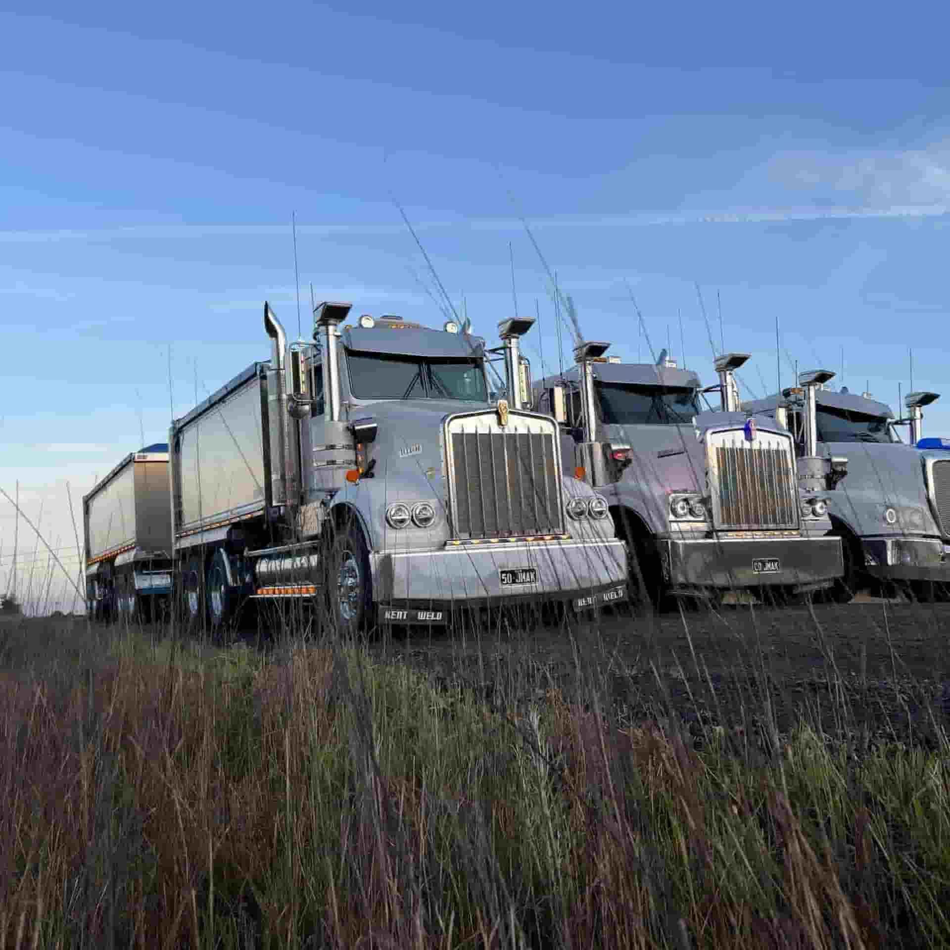 A Row Of Semi Trucks Are Parked In A Field — JMAK Haulage & Landscapes Supplies In Nowra, NSW