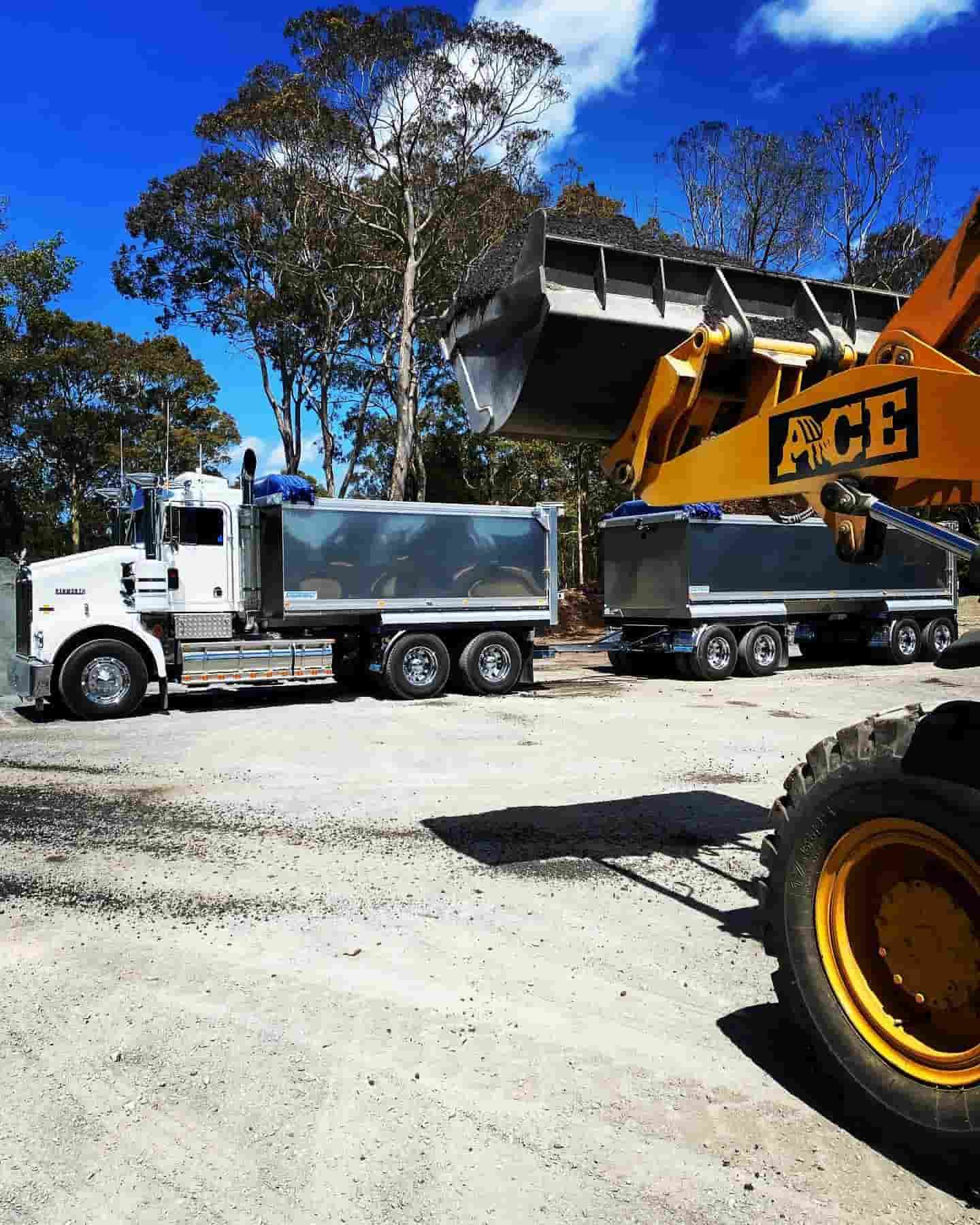 A Dump Truck Is Being Towed By An Excavator — JMAK Haulage & Landscapes Supplies In Nowra, NSW